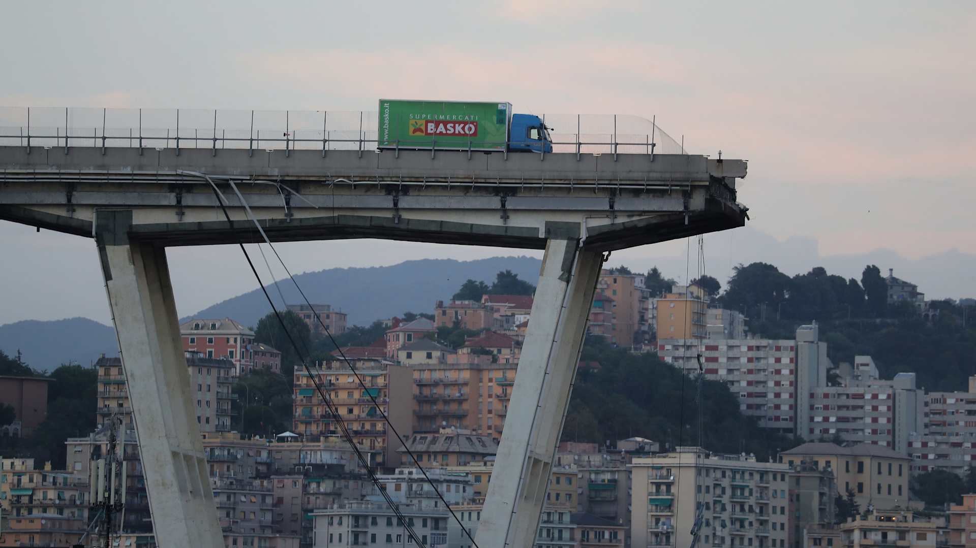 A lorry stands on the edge of the collapsed Morandi motorway bridge in the northwestern city of Genoa on August 14, 2018. - About 30 people were killed when a giant motorway bridge collapsed in heavy rain in the Italian city of Genoa in what the government called an "immense tragedy". The collapse, which saw a vast stretch of the A10 freeway tumble on to railway lines in the northern port city, came as the bridge was undergoing maintenance work and as the Liguria region, where Genoa is situated, experienced torrential rainfall.