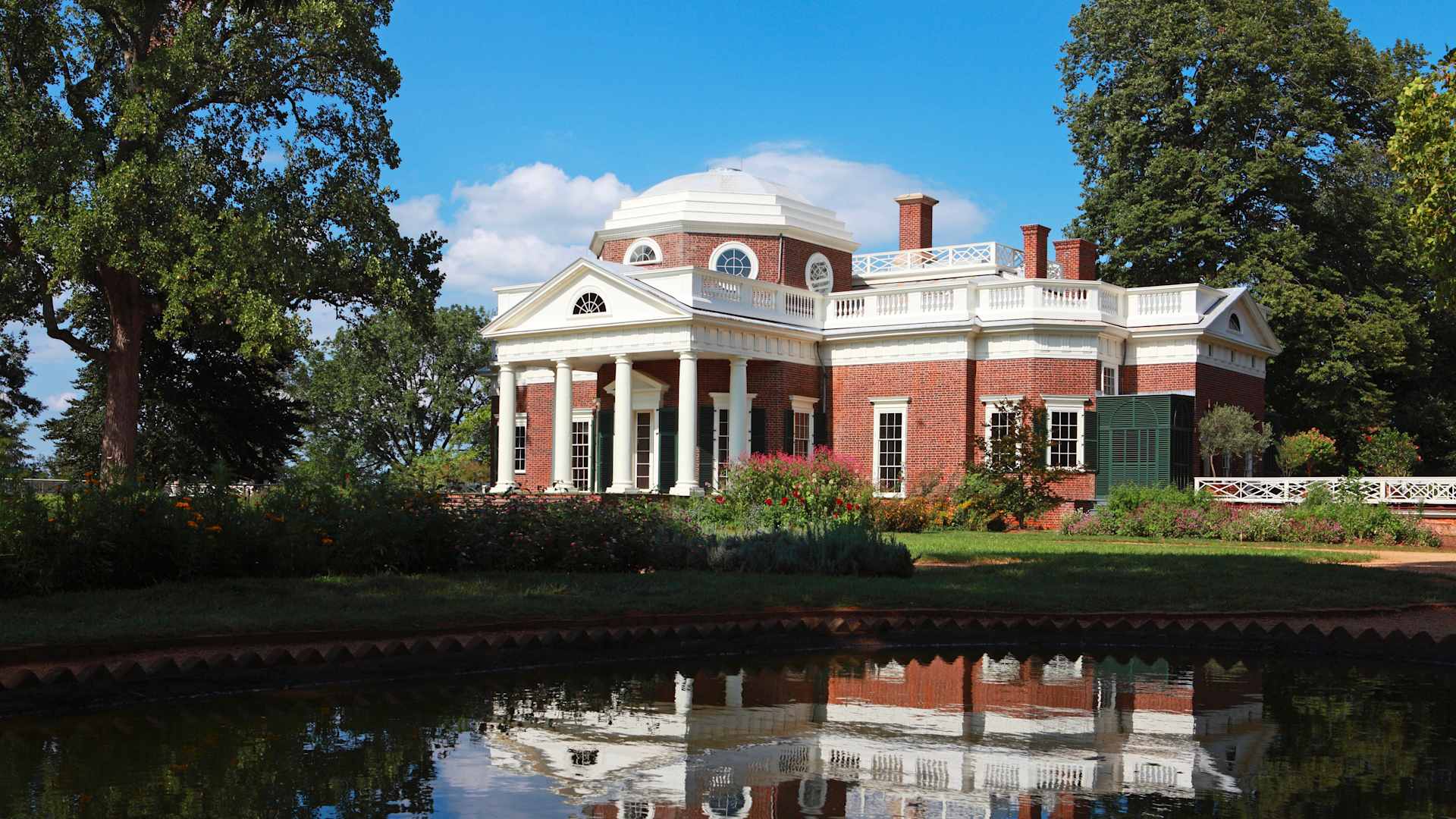 Exterior view of the Monticello, Thomas Jefferson's Virginia home, with its red-brick exterior, neoclassical columned portico and white-topped dome.