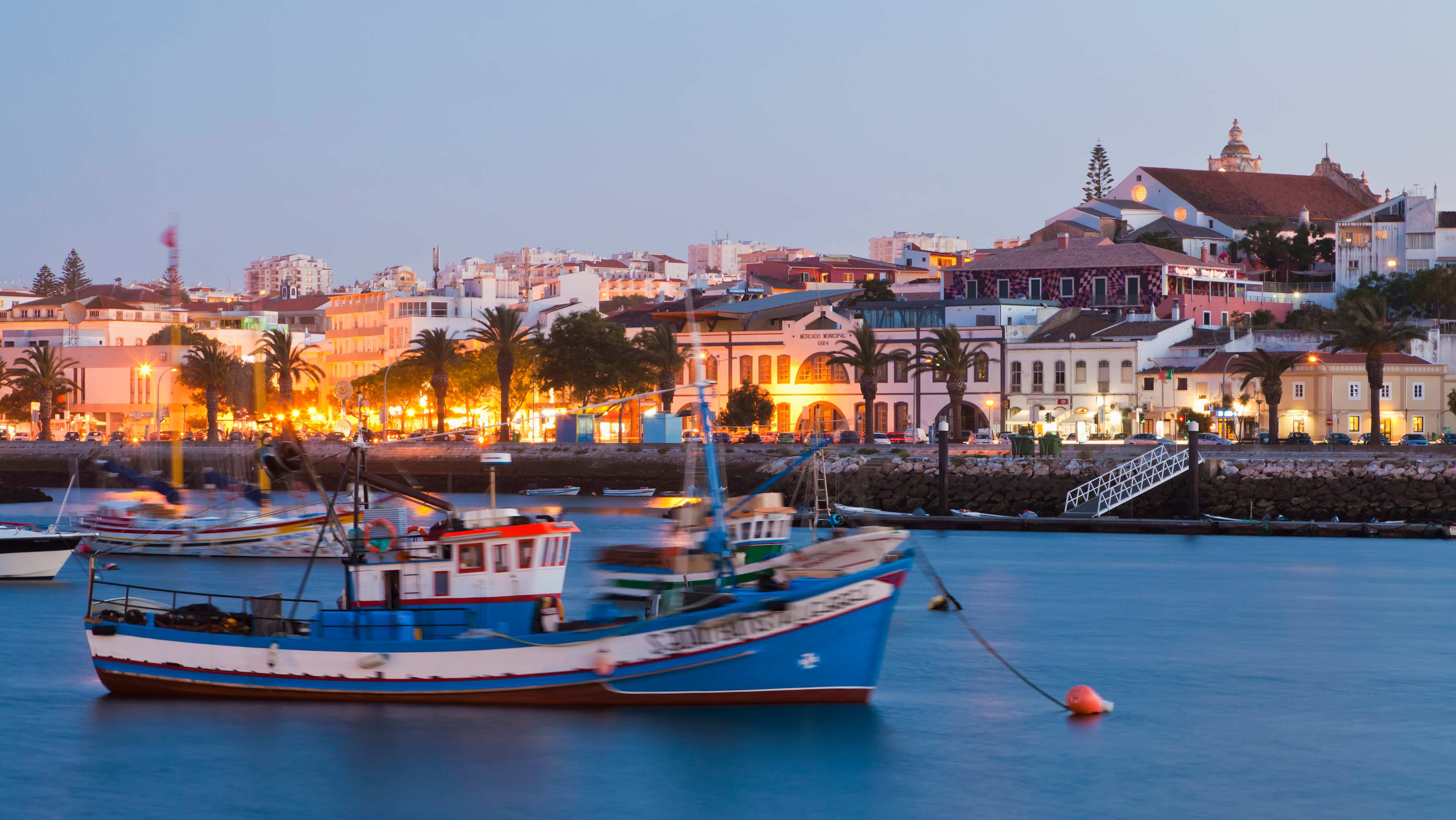 Portugal, Lagos, View of fishing boat at harbour and city in background