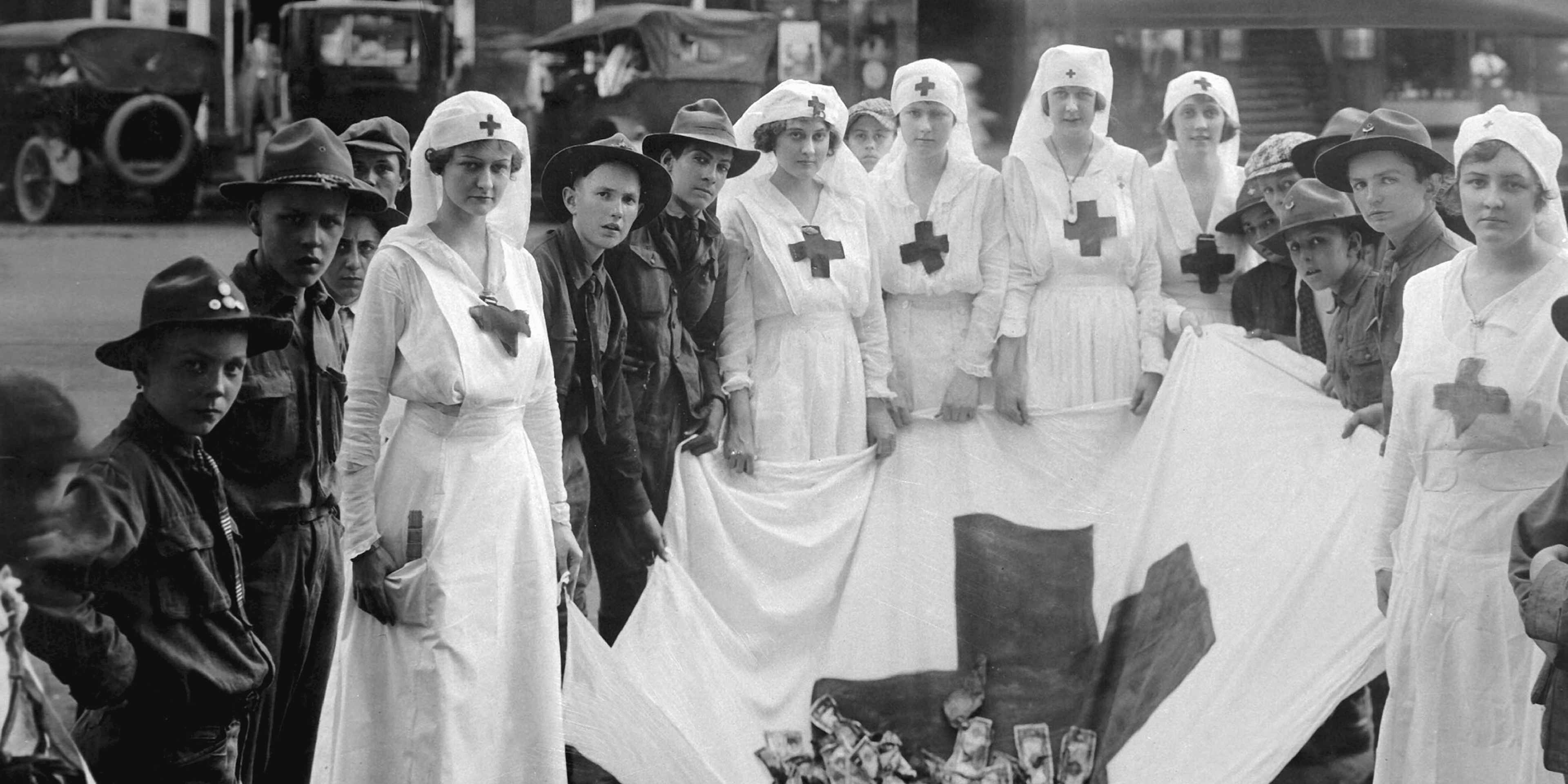 Group portrait of female American Red Cross workers with uniformed young boys (possibly boy scouts) with a Red Cross flag holding money, during a Red Cross parade, Birmingham, Alabama, May, 1918. US War Department photo.