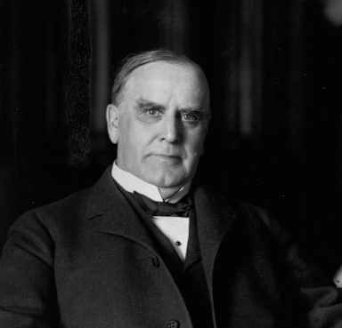 Black and white photo of President William McKinley seating in a suit and staring straight at the camera