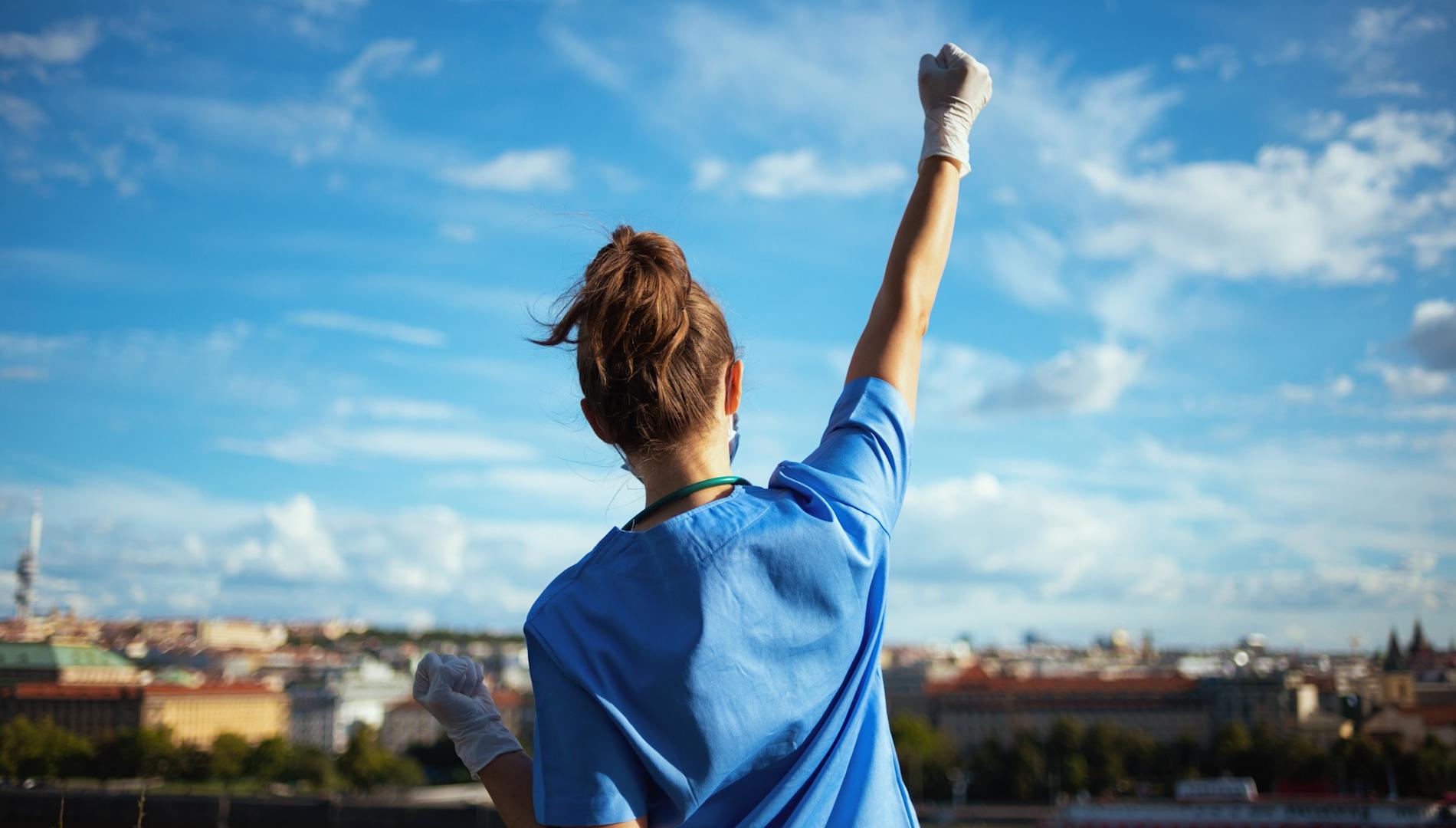 A nurse standing and punching her fist in the air.