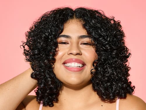 woman smiling and touching her dark curly hair
