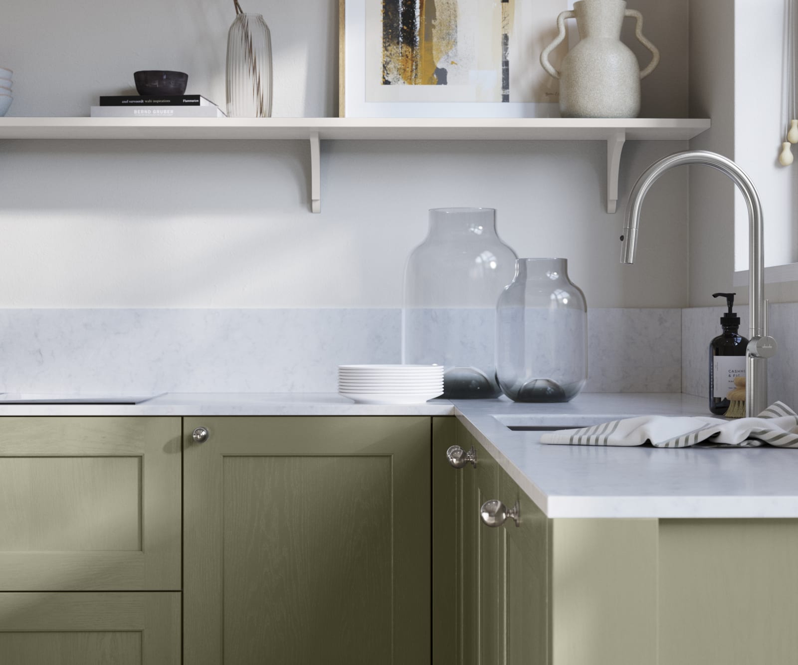Ludlow, a traditional Shaker-style premium feel kitchen range with a visible woodgrain on its panelled doors here shown in the green shade Misty moors styled with steel knobs, steel tap, a white marbled worktop with matching splashback.