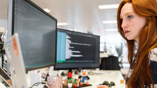 Woman working at desk with two screens, technology modernisation