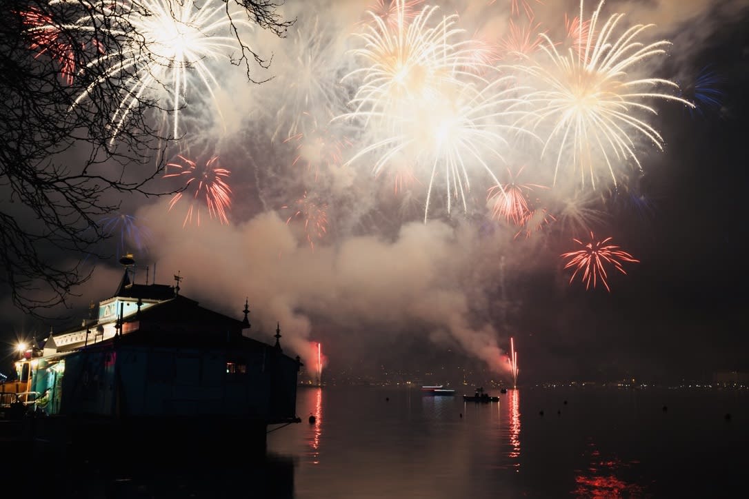Fireworks light up the night sky above a calm body of water, with a silhouetted building in the foreground, capturing the magic of NYE 2024/2025 celebrations at one of the city's vibrant LGBTQ+ hotspots. This year's gay New Year's Eve promises to be unforgettable, as friends and allies gather to usher in new beginnings and embrace diversity under the dazzling display.