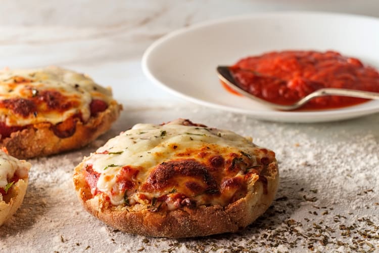 English-muffin pizzas in front of a saucer of sauce