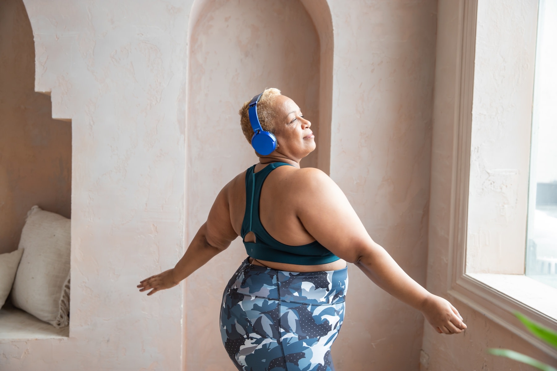 A woman dancing while wearing exercise clothes and headphones.