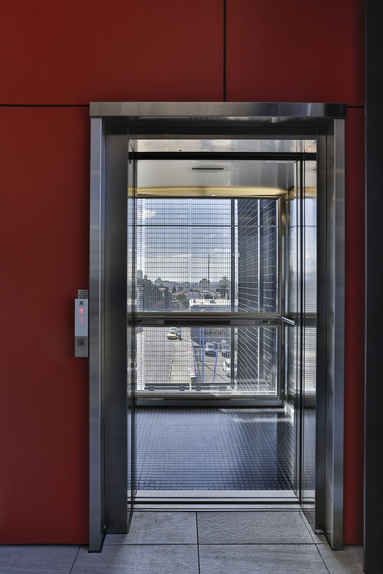 An external elevator with a stainless steel and architecture, door, facade, glass, window, red, gray